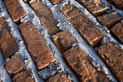A high-angle close-up shot of a textured red brick wall with thick, rough c.. Stock Photos
