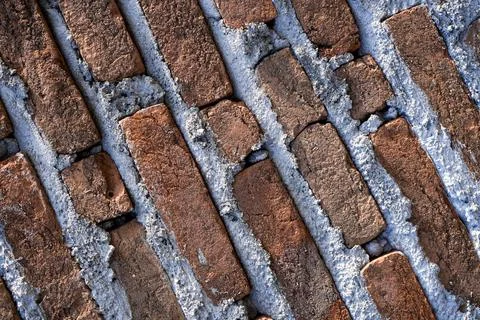 A high-angle close-up shot of a textured red brick wall with thick, rough c.. Stock Photos