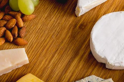 High angle close-up shot of various cheese with grapes and almonds on wooden Stock Photos