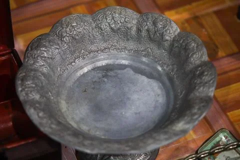 High angle close up view of antique carved metal brass bowl dish on wooden .. Stock Photos