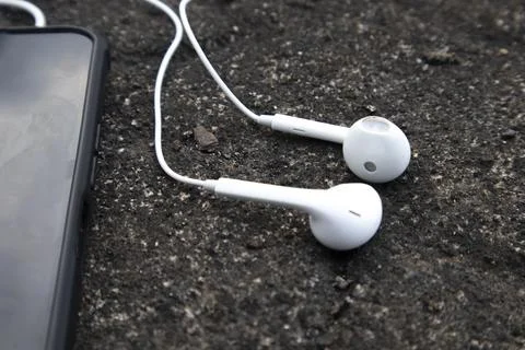 High angle close up view of a pair of white wired earphones plugged into a .. Stock Photos