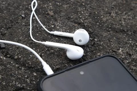 High angle close up view of a pair of classic white wired earphones plugged.. Stock Photos