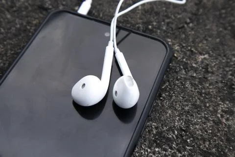 High angle close up view of a pair of white wired earphones plugged into an.. Stock Photos