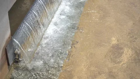 High-Angle Close-Up of Water Cascading Over Metal Weir into Treatment Basin Stock Footage 334623202