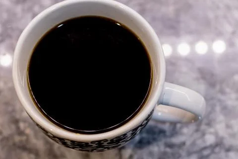 High angle closeup shot of a white cup with black patterns filled with coffee Stock Photos