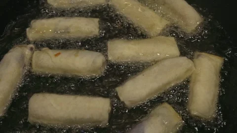 High angle closeup of springrolls frying in hot oil in stovetop pan Stock Footage 301489800