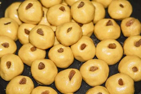 A high-angle composition of numerous golden milk peda sweets with raisin centers 스톡 사진