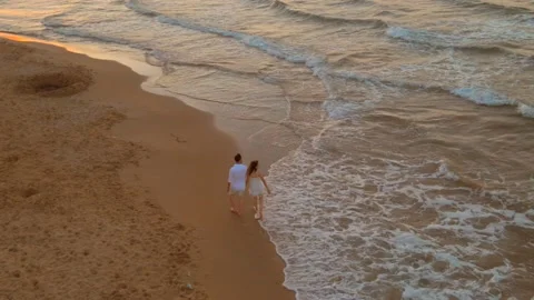 High angle of a couple walking and drawing a heart near the waves washing over t Vídeo Stock 220357718