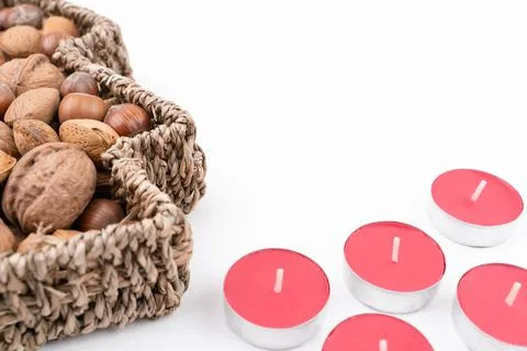 High angle detail studio shot of basket full of mixed nuts and red tea candles Stock Photos