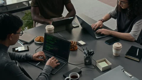 High Angle of Developers Working on Tablet and Laptops at Pushed Together Desks Stock Footage 329612489