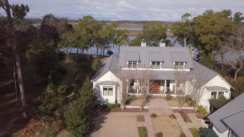 High angle dolly shot of beautiful waterfront home with porch and metal roof. Video stock 128995550