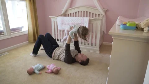 High angle dolly shot of father lifting daughter while lying on floor at home Stock Footage