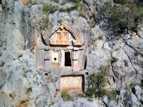 High angle drone aerial view of ancient greek rock cut tombs carved into clif Фото