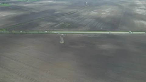 High angle drone flies over a high voltage pole and plowed fields Stock Footage 271298193