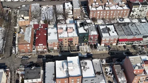 High angle drone footage flying over snow covered rooftops of brick apartment 스톡 동영상 331075812