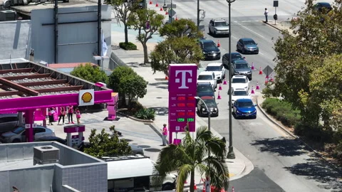 High angle drone shot of long car lines waiting for a T-Mobile fuel promotion Stock Footage 339642621