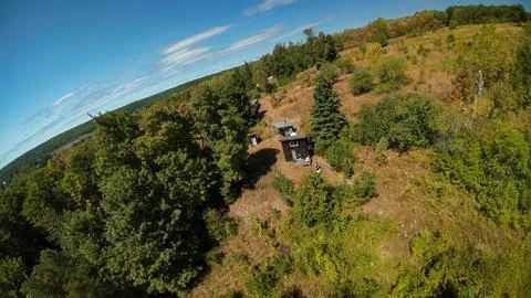 High angle drone shot looking down at a tiny off grid cabin on a grassy hill Stock-Fotos