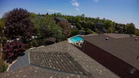 High angle drone shot looking over a house roof toward backyard pool properti Foto stock