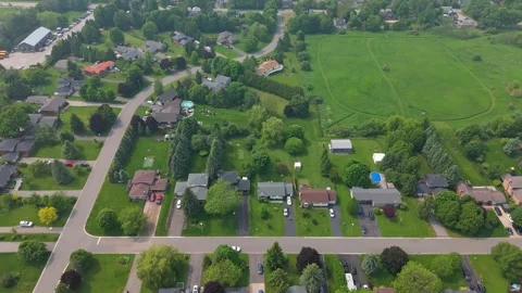 High-angle drone shot over a green suburban subdivision with curving roads Stock Footage 325832794