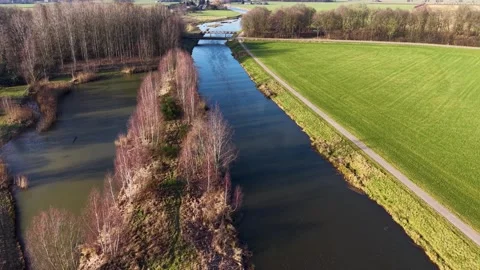 High-angle drone shot of a peaceful blue canal winding through lush green fields 動画素材 330283268