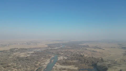 A high-angle drone shot of a winding river crossing a flat valley. Stock Footage 331176619
