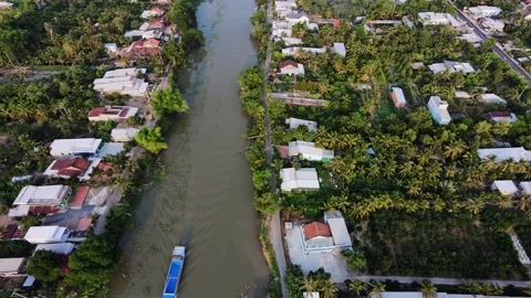 High angle drone tracking shot of boat along Mekong Delta village Vídeos de archivo 335809355