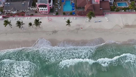 High angle drone tracking shot over ocean waves crashing onto the white sand Vídeo Stock 336705699