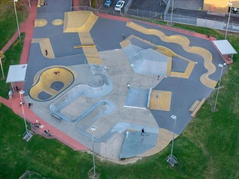 High-angle drone view captures a modern concrete skatepark bustling with sk.. Stock Photos