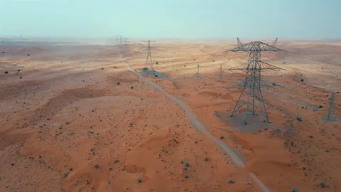 A high-angle drone view of High-voltage electric poles in the desert in UAE Stock Footage 333471116
