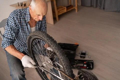 High angle elderly man repairing bicycle at home overhead view Stock Photos