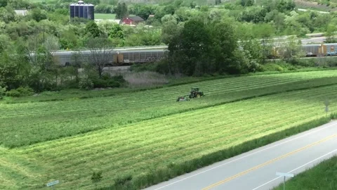 A High Angle Establishing Shot of a Farm Tractor and a Freight Train Stock-Footage 196177322