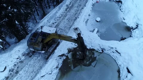 High Angle Excavator Breaking Pond Ice Drone Shot Stock Footage 146613088