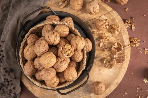 A high-angle flat lay featuring a woven basket packed with whole walnuts si.. Stock Photos