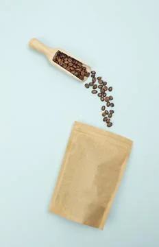 High-angle flat lay of a scoop pouring coffee beans into a paper eco bag, d.. Stock Photos