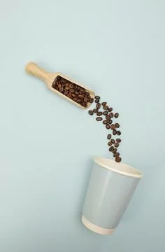 High-angle flat lay of a scoop pouring coffee beans into a paper cup, desig.. Stock Photos