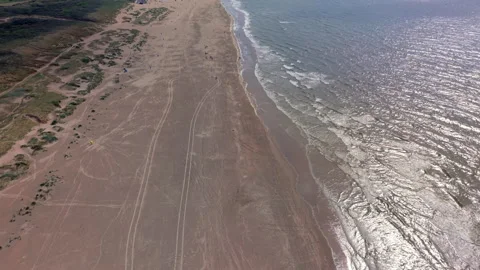 High angle horizontal aerial drone video clip of sandy beach with tire track Stock Footage 342668926