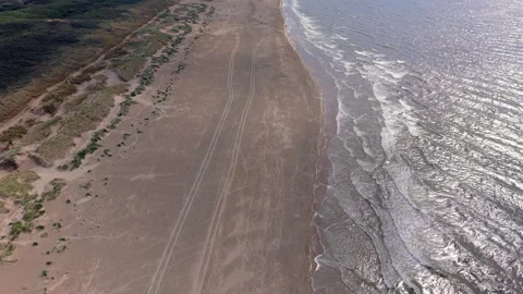 High angle horizontal aerial drone video clip of sandy beach with tire track Stock Footage 342737074