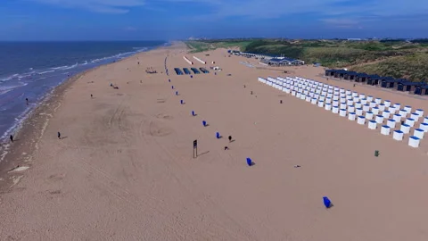 High angle horizontal aerial drone video clip of sandy beach, white cabins Видео 342819752