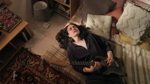 High Angle of Man Lying Down and Playing Electric Guitar with Eyes Closed Stock Footage 338064296