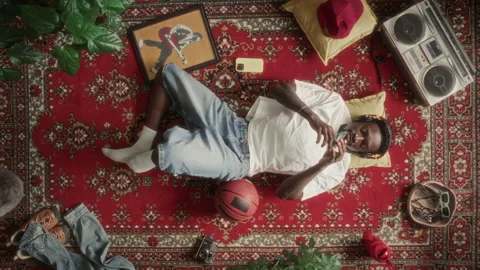 High Angle of Man Lying on Rug, Holding Cassette Tape and Listening to Music Stock Footage 339846099