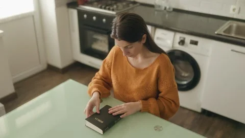 High Angle One Woman Sitting At Kitchen Table Closing Holy Bible Stock Footage 334041095