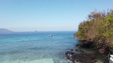 High Angle of Outrigger Boat and Rocky Coast at Blue Lagoon Beach Bali Indonesia Stock Footage 339751647
