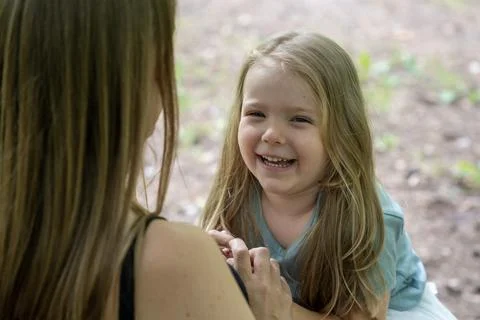 High angle over-the-shoulder portrait of a laughing child on mother's knees Stock Photos