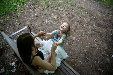 High angle, over-the-shoulder shot of a laughing daughter on mother’s lap Stock Photos