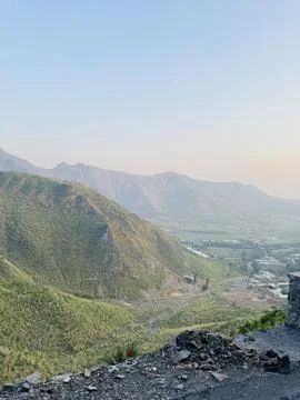 High-Angle Panoramic View of a Hazy Valley and Settlement below Green Mount.. Stock Photos