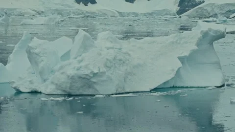 High Angle Parallax Shot Moving Past Massive Sculpted Iceberg in Calm Antarctic Vídeos de archivo 334104258
