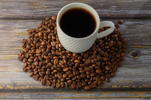 High angle perspective of white coffee cup and roasted beans on wood Stock Photos