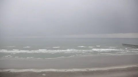 High angle of rainy misty beach with a pier Stock Footage