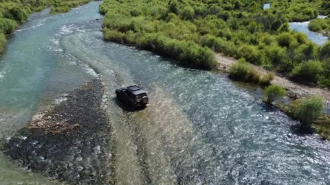 High angle rear view of black 4x4 off-road vehicle navigating through river Vidéo 334624963