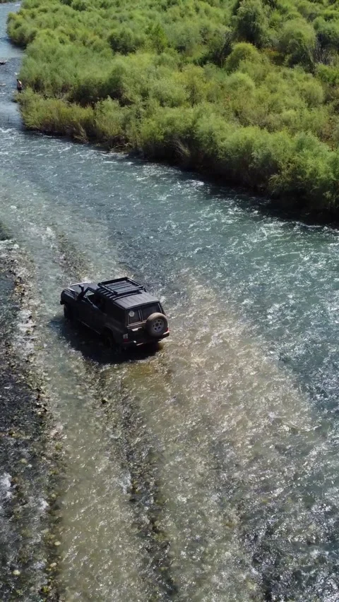 High angle rear view of black 4x4 off-road vehicle navigating through river Stock Footage 336690829